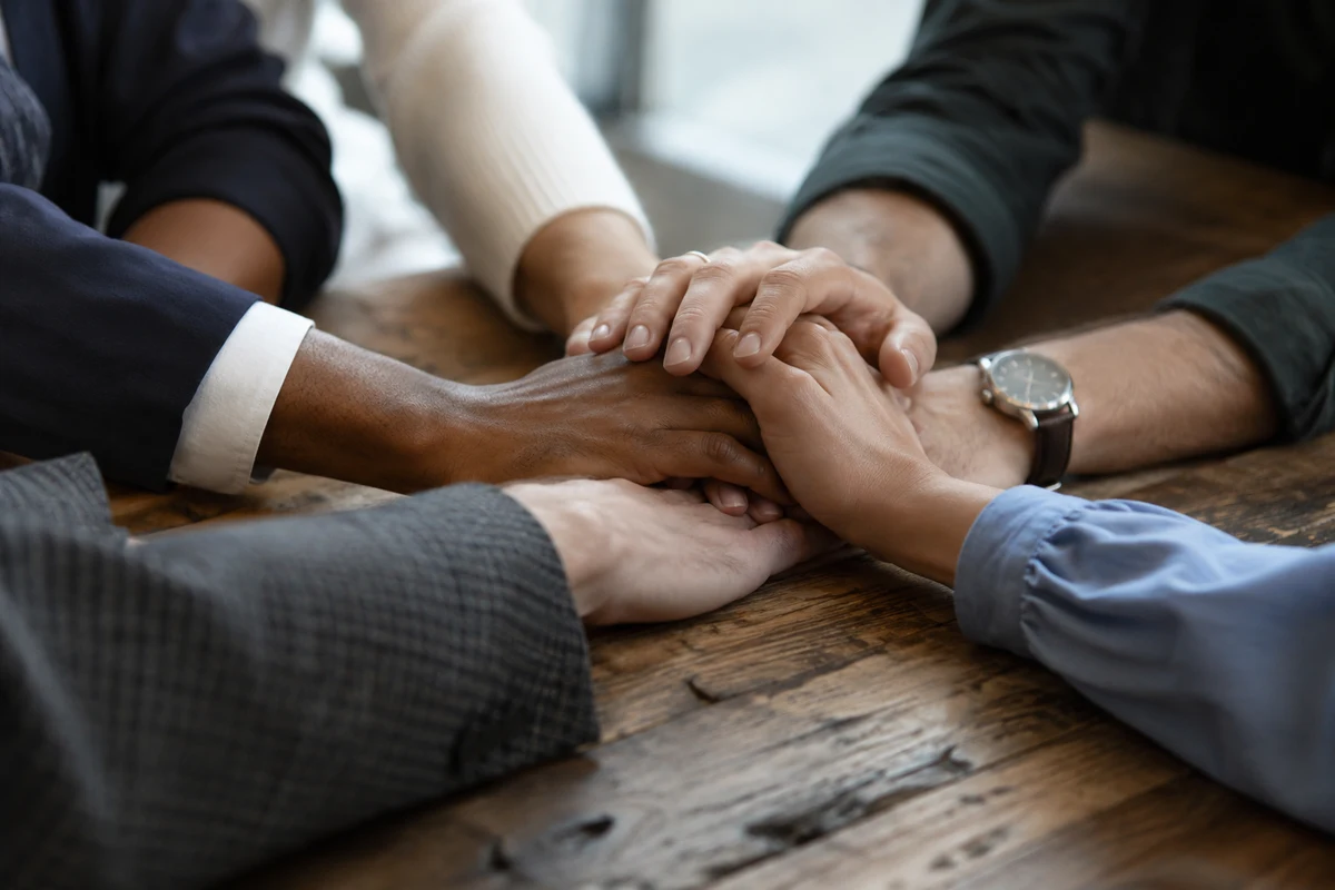 Several pairs of hands over papers on a shared table.